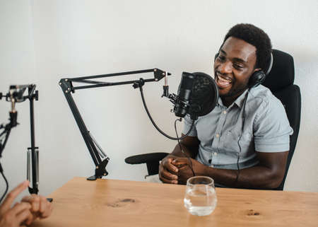 Black man recording podcast with crop colleagueの写真素材