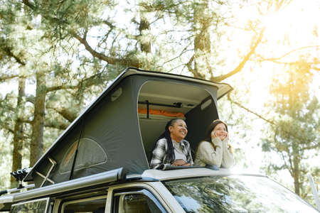 Diverse traveling women relaxing in tent on roof of carの写真素材