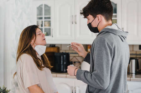 Teenage guy taking PCR test from mother at home during COVID pandemic