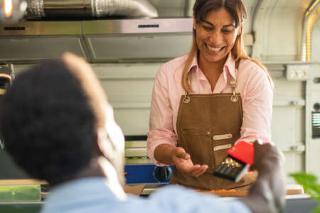 Black man making payment with smartphone in food truckの写真素材
