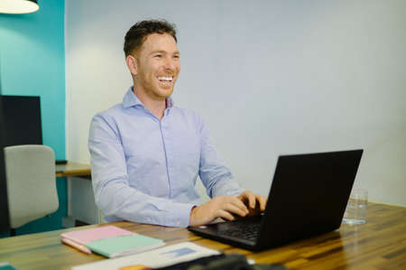 Positive businessman typing on laptop in coworking space