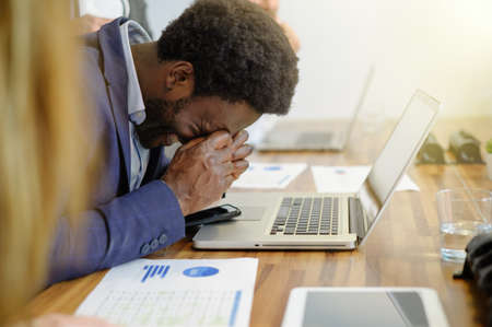 Tired black businessman with headache working in office