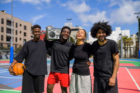 Cheerful black sportspeople with boombox on playgroundの写真素材