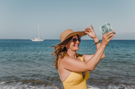 Joyful woman with fan on shoreの写真素材