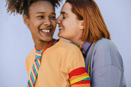 Smiling diverse lesbian couple embracing in studioの写真素材