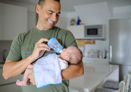 Happy father feeding newborn baby