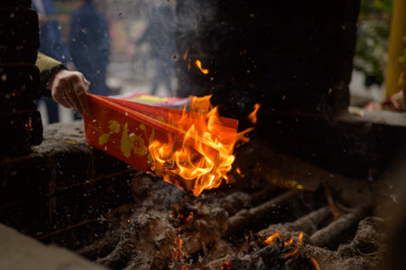 Crop unrecognizable person burning red votive paper on bonfire on street of Hoi An in Vietnamの写真素材