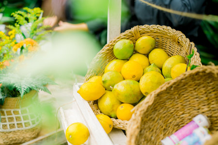 Fresh lemons in wicker basket with flowersの写真素材