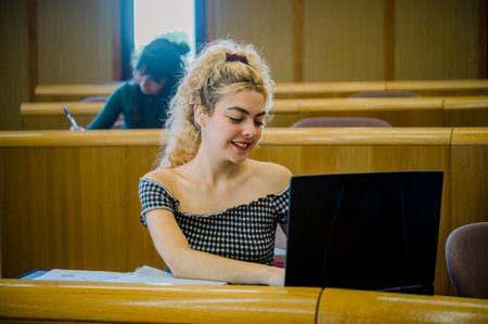 Smiling young woman using laptop in classroomの写真素材