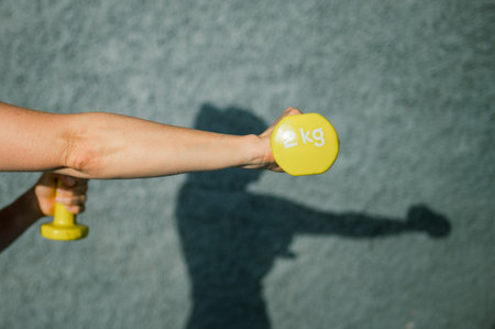 Colorful dumbbells in hands of sportswomanの写真素材