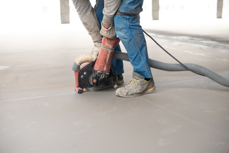 Crop anonymous man leveling floor with machine during constructionの写真素材