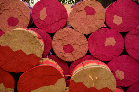 Rolls of colorful incense sticks tied with ribbons placed on each other in rows in manufactureの写真素材