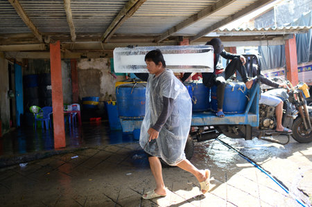 Ethnic man carrying a block of ice on the streetのeditorial素材