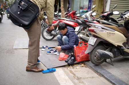 Man cleans boots on the street surrounded by motorcyclesのeditorial素材
