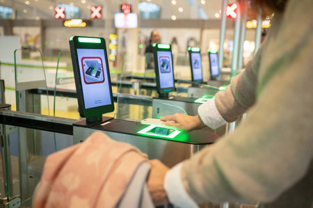 Crop woman using smartphone while scanning info into smart gate pass in airportの写真素材
