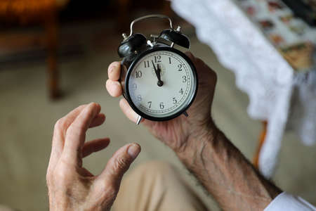Man holding hand on black alarm clock.の写真素材