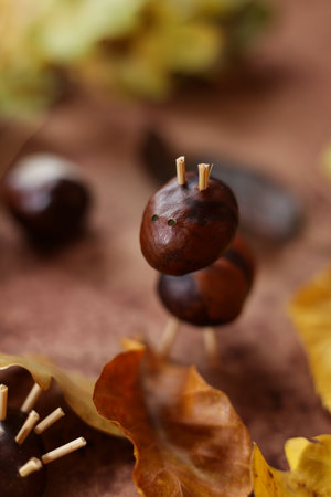still life with colorful autumn leaves and animals made of horse chestnuts on a brown watercolor backgroundの写真素材