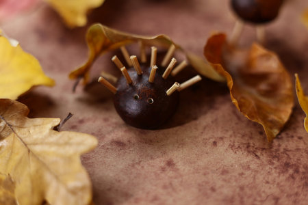 still life with colorful autumn leaves and animals made of horse chestnuts on a brown watercolor backgroundの写真素材