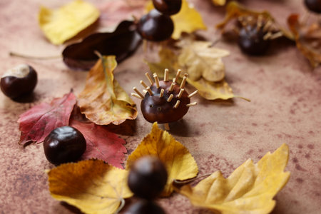 still life with colorful autumn leaves and animals made of horse chestnuts on a brown watercolor backgroundの写真素材