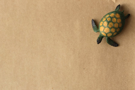 green toy turtle on a brown paper backgroundの写真素材