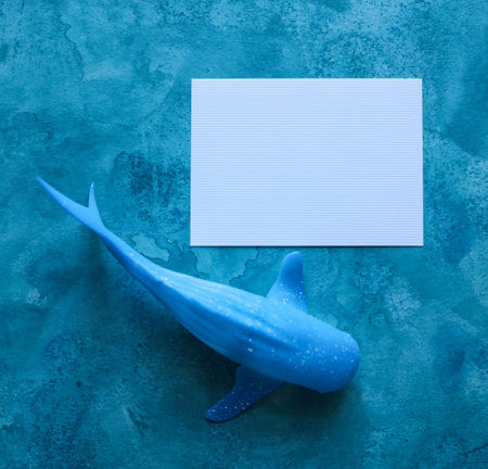 toy whale with a blank paper card with a blue watercolor backgroundの写真素材