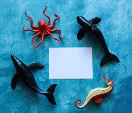 a close up of a blank note card with sea life animal toys on a blue watercolor backgroundの写真素材