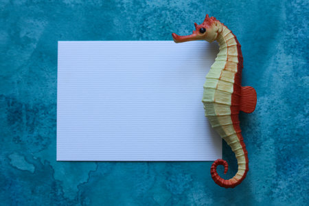 blank paper card with a toy seahorse on a blue watercolor backgroundの写真素材