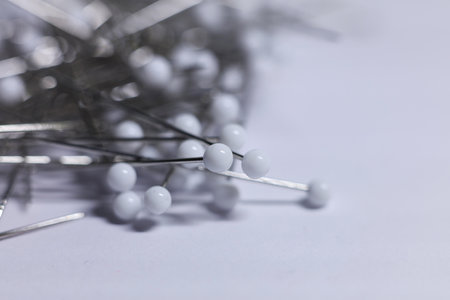close up of sewing pins on white background with shallow depth of field