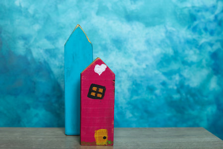 Wooden toy house on wooden table. Blue background. Copy space.の写真素材