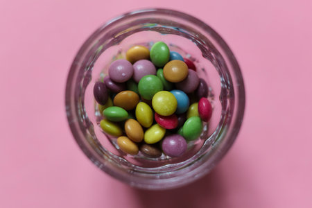 Colorful candies in glass on pink background. Top view.の写真素材