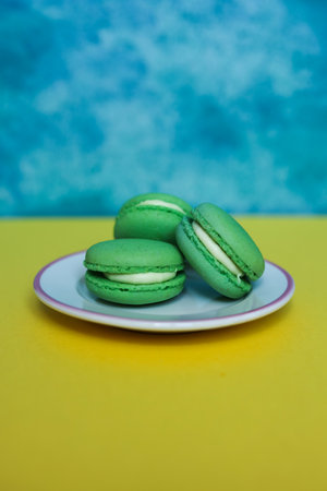 Green macarons on a blue and yellow background with copy spaceの写真素材