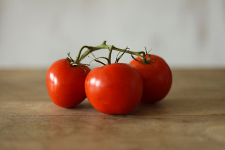 tomatoes on a wooden table in front of a white wall.の写真素材