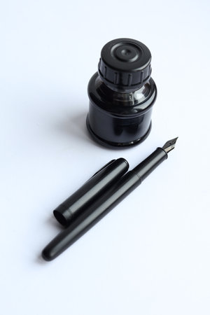 Black ink pen and ink bottle isolated on a white background with copy spaceの写真素材