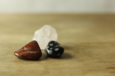 Closeup of red and black minerals and pink quartz stone on a wooden table.