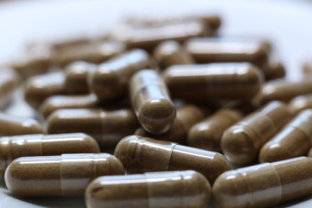 Close-up of a pile of brown pills on a white plateの写真素材