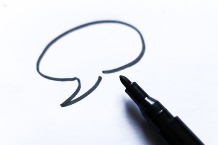 Black marker pen with hand drawn speech bubble on white paper. Minimal creative concept for communication, dialogue, ideas, brainstorming, and graphic design themes.の写真素材