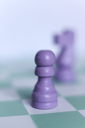 Close-up of a purple chess pawn on a mint green chessboard. Minimalistic macro photograph symbolizing strategy, logic, leadership, and decision-making in soft pastel tones.の写真素材