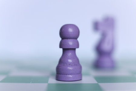 Close-up of a purple chess pawn on a mint green chessboard. Minimalistic macro photograph symbolizing strategy, logic, leadership, and decision-making in soft pastel tones.の写真素材