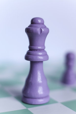 Macro photograph of a purple chess queen standing on a mint green and white chessboard. Minimalistic pastel compositionの写真素材