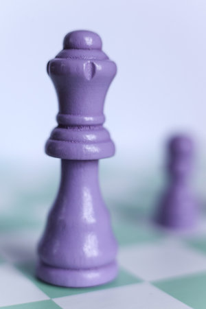 Macro photograph of a purple chess queen standing on a mint green and white chessboard. Minimalistic pastel compositionの写真素材