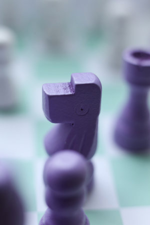 Macro photograph of a purple chess knight piece on a mint green and white chessboard. Minimalistic and creative conceptの写真素材