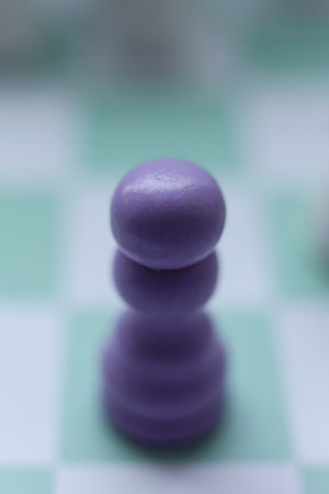 Close-up of a purple chess pawn on a mint green chessboard. Minimalistic macro photograph symbolizing strategy, logic, leadership, and decision-making in soft pastel tones.の写真素材