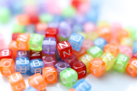 Close-up macro photograph of vibrant, translucent alphabet beads in assorted colors. Soft selective focus and bright playful tonesの写真素材