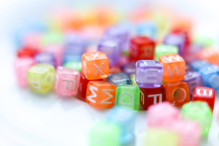 Close-up macro photograph of vibrant, translucent alphabet beads in assorted colors. Soft selective focus and bright playful tonesの写真素材