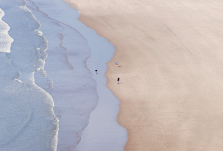 people with dog walking on the sandy beach on windy wavy day on the wales south coastの写真素材