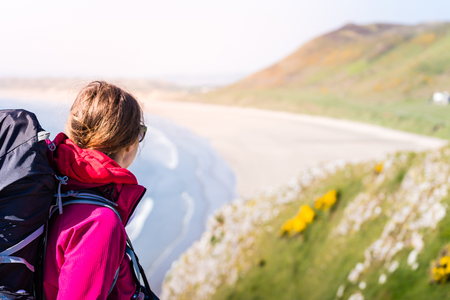 Young Woman Looking To Distance From A Cliff Over The Seashore In Rhossili, Wales Coast Path