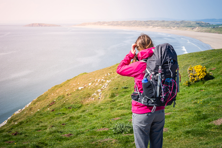 Young Woman Looking To Distance From A Cliff Over The Seashore In Rhossili, Wales Coast Pathの写真素材