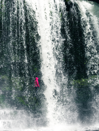 Feamale hiker, tourist, model standing or walking under the Sgwd Yr Eira Waterfall in Wales. In Portrait framing. の写真素材