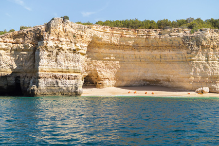 Hidden remote beach covered with limestone walls. Kayak left on the beach by tourists went for cave exploring. Algarve Portugal.の写真素材