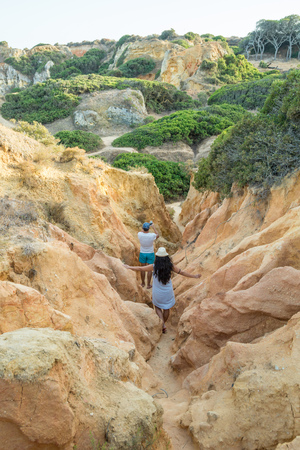 People hiking between the hills of Praia dos Pinheiros in Lagos, Portugal.のeditorial素材